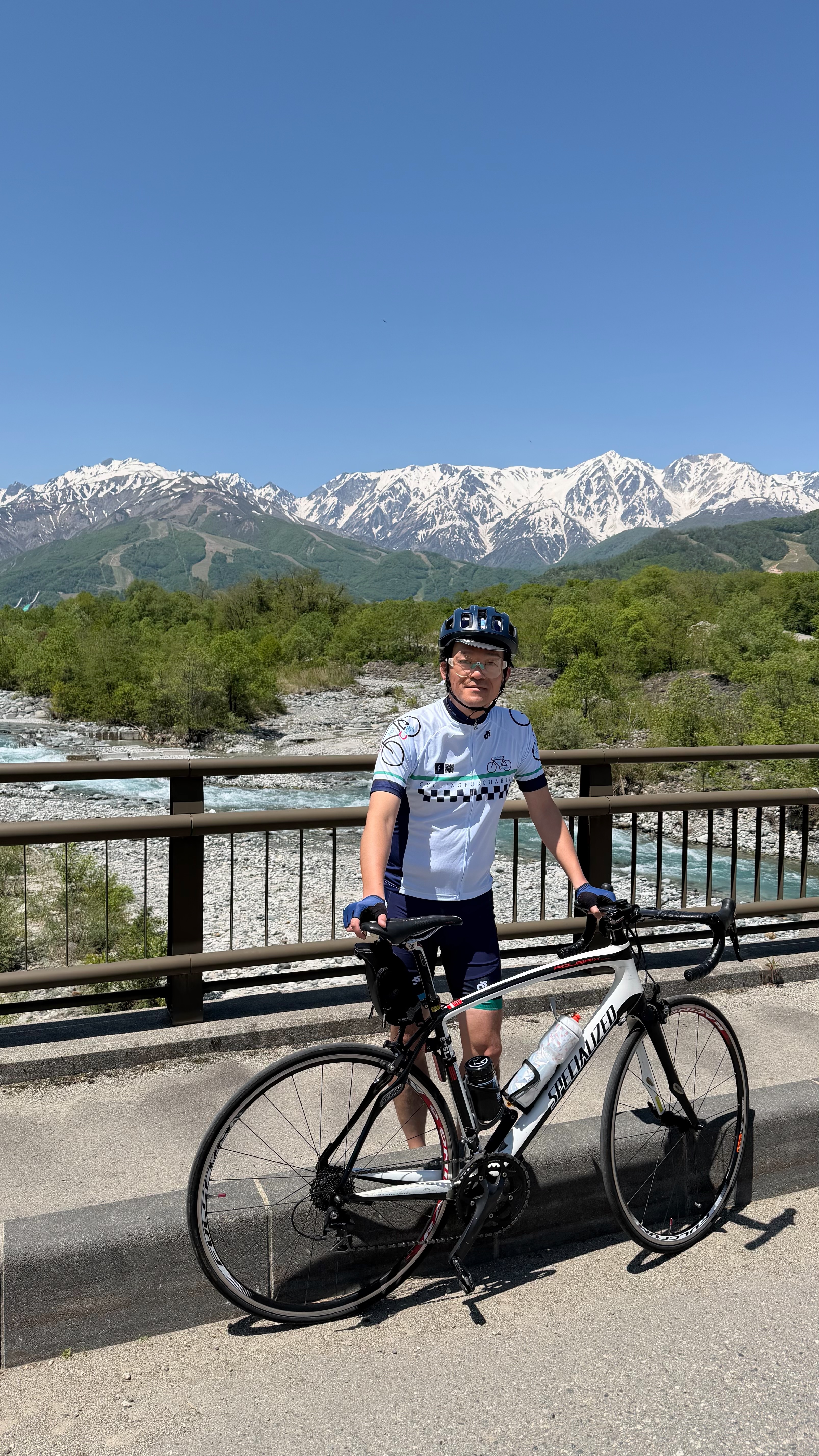 2026 North Alps — cyclist on bridge with Alps backdrop